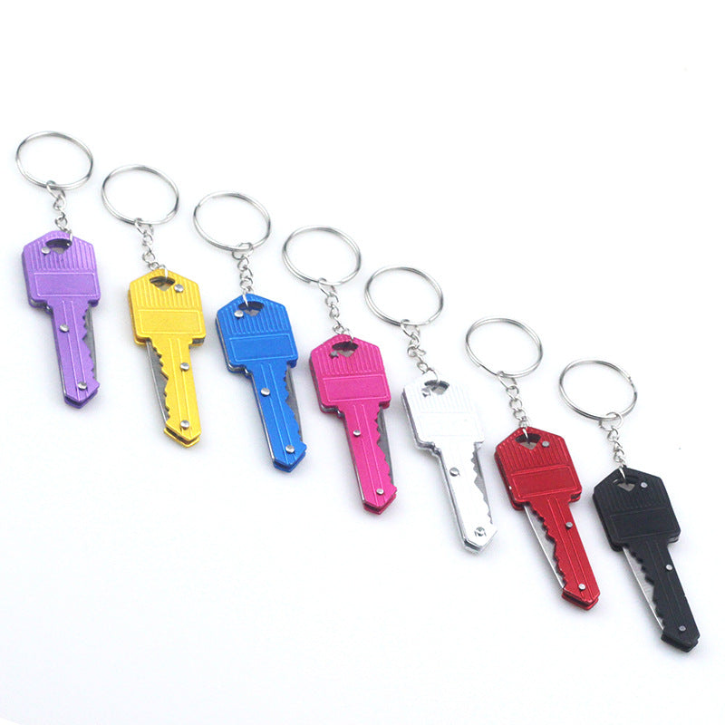Set of seven colorful metal key-shaped keychains in purple, yellow, blue, pink, white, red, and black, each attached to a silver key ring, displayed on a white background.